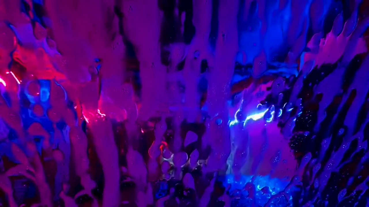 Colorful foam and blue lighting inside Jeff’s Express wash tunnel